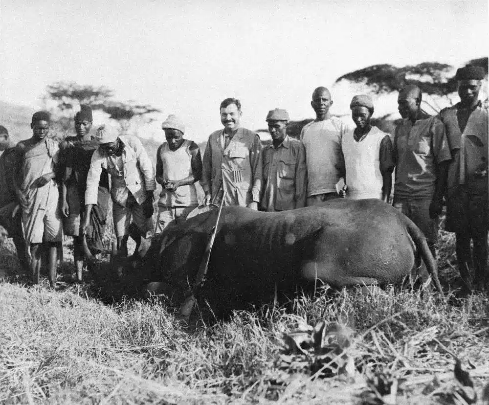 Ernest Hemingway posing with a hunted rhino on safari